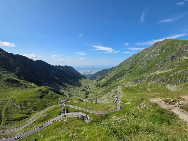 Die Transfăgărășan-Hochalpenstraße schlängelt sich durch ein üppig grünes Bergtal.
