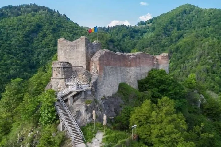 Luftaufnahme der Burgruine Poenari auf einem bewaldeten Hügel.