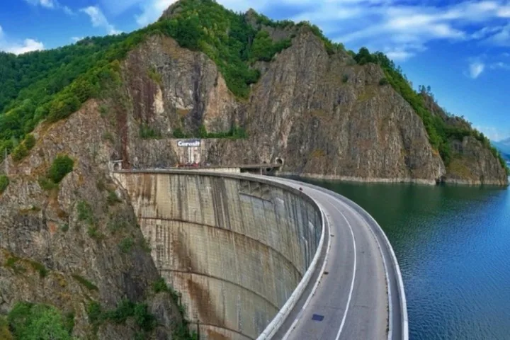 Struttura curva in cemento della Diga di Vidraru con una strada in cima.